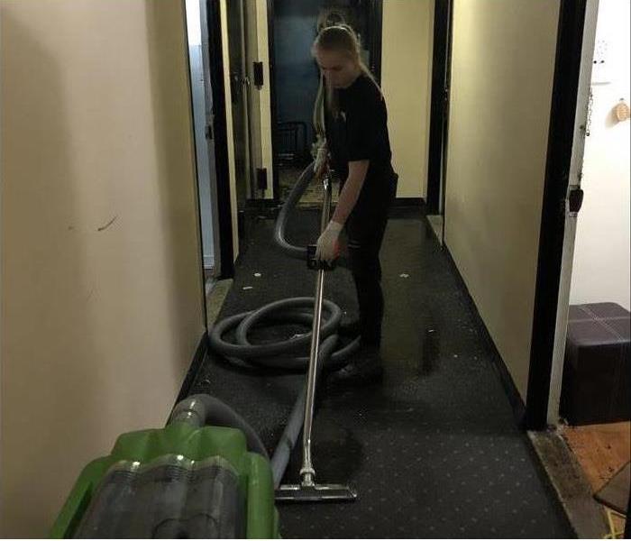 tech vacuuming wet corridor in building